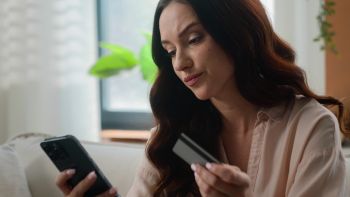 Kobieta z kartą kredytową i telefonem smutna