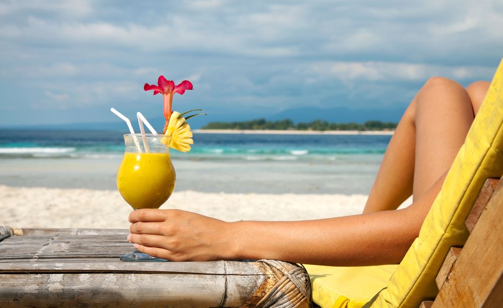 Kobieta na plaży z drinkiem w dłoni