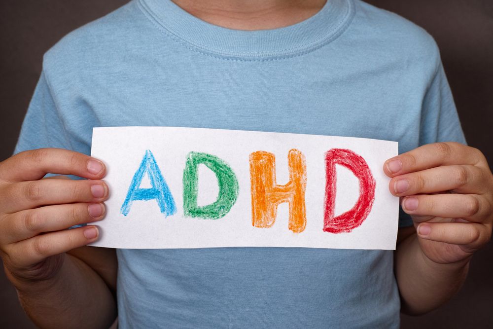 Młody chłopak trzyma kartkę z napisem ADHD