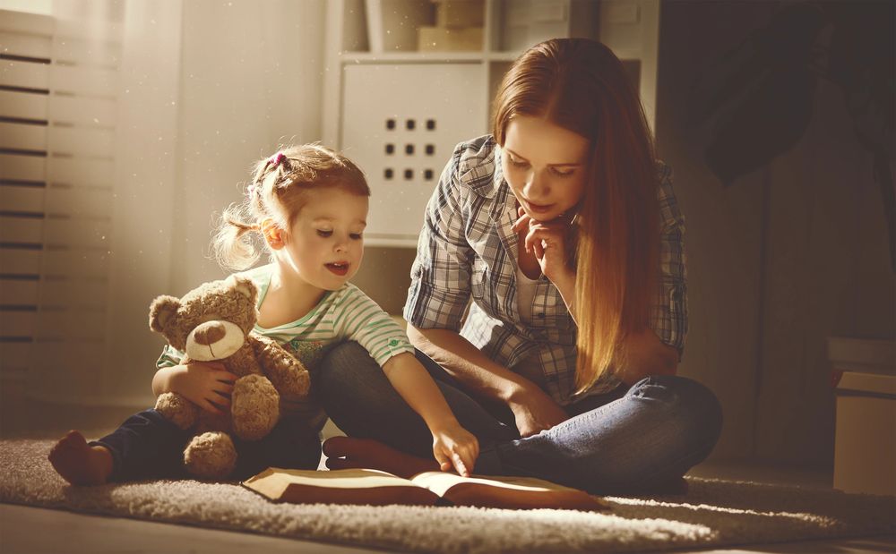 Mama i córka czytają razem książkę na dywanie