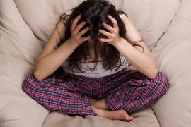 Leczenie zaburzeń używania substancji wśród młodzieży. Sfrustrowana dziewczyna siedzi na łóżku z głową w rękach