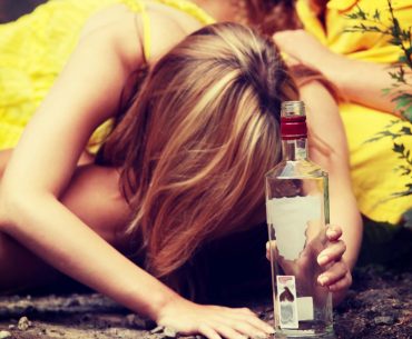 Pijana kobieta z butelką w ręku na żółtym tle