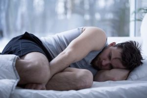 Zaburzenia snu osób uzależnionych. Mężczyzna w łóżku nie może usnąć