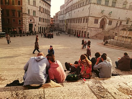 Grupa ludzi siedzi na placu